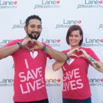 Image of a man and a woman wearing shirts that say "I save lives" making their hands into hearts